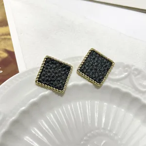 Retro black and gold square earrings detail close-up, elegant geometric vintage chic ear studs.