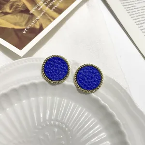 Close up detail of vintage blue textured round stud earrings featuring gold twisted rims on plate.