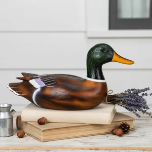 Detailaufnahme einer Mallard-Ente Deko-Figur auf Vintage-Büchern mit echtem Lavendel.