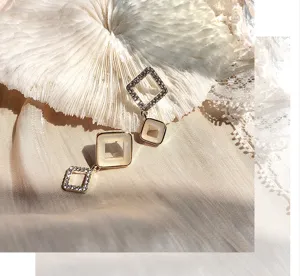 Gros plan de boucles d'oreilles géométriques carrées en strass avec des cristaux brillants.