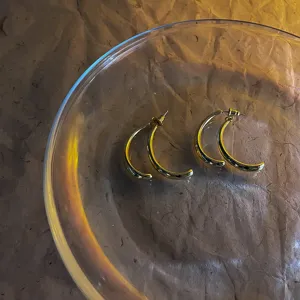 Detail view of stylish gold metal curved C-shaped earrings, elegant daily jewelry accessory.