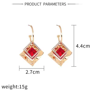 Detailed view of luxury gold geometric red crystal drop earrings with sparkling rhinestones.