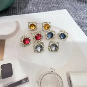 Gros plan d'élégantes boucles d'oreilles carrées en cristal aux pierres colorées.