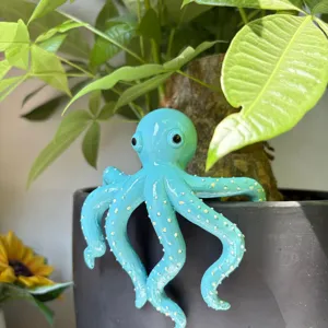 Figurine de poulpe en résine bleue suspendue à un pot de fleurs, beau détail de déco.