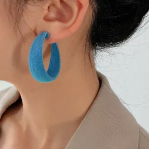 Close-up of blue velvet hoop earrings, retro chunky style detail showing soft texture.