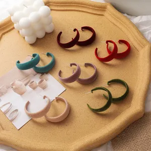 Close-up detail of colorful velvet hoop earrings, retro style jewelry display scene.