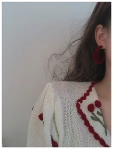 Close-up detail shot of vintage red velvet hoop earrings, retro chic ear accessories.