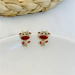 Primo piano dettagliato di orecchini a forma di bue con smalto rosso e strass brillanti.