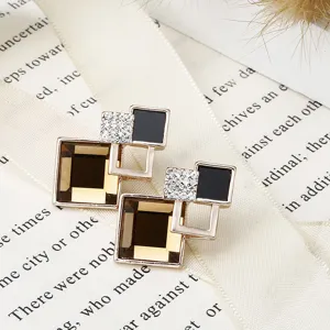 Close-up detail van geometrische kristallen oorringen met gouden rand en strass, elegante stijl.