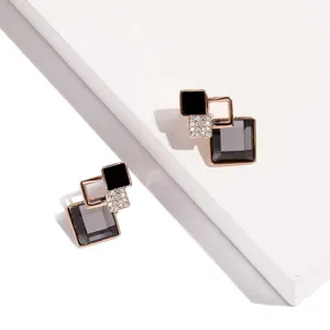 Detailopname van geometrische vierkante oorbellen met fonkelende strass-steentjes en pracht.