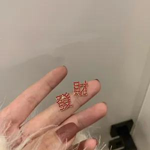 Gedetailleerd overzicht van trendy oorknopjes met strass en Chinese karakters in goud.