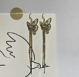 Close-up detail of elegant gold butterfly long tassel earrings with sparkling rhinestones.