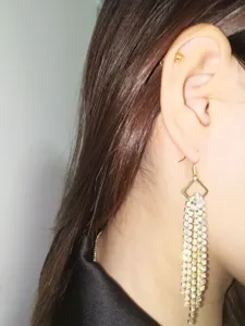 Close-up view of elegant long rhinestone tassel earrings sparkling on ear, stylish detail.