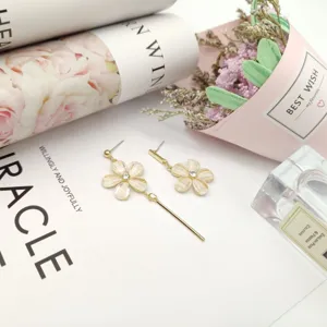 Close-up detail of trendy asymmetrical flower tassel earrings in gold, elegant design for women.