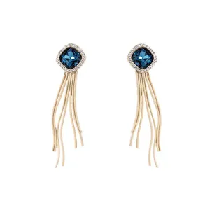 Vue détaillée des boucles d'oreilles en cristal carré et franges dorées, texture fine.