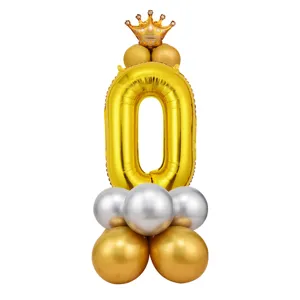 Vue détaillée du ballon en aluminium chiffre 0 doré avec couronne et ballons en latex.