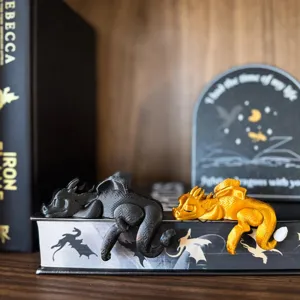 Detailed close-up of resin sleeping dragon bookshelf sitters in black and gold finishes.