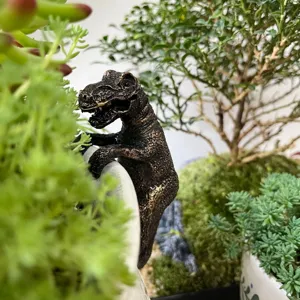 Gros plan détaillé d'un ornement de pot dinosaure T-Rex en résine dans un jardin miniature.