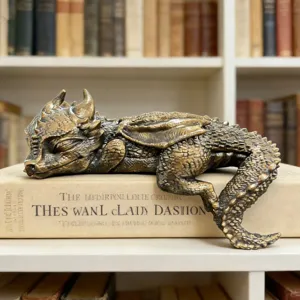 Detailed view of a sleeping baby dragon resin sculpture resting on a vintage book in a study.