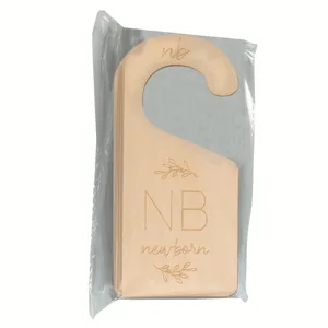 Close-up detail of wooden baby closet size dividers, double-sided engraved newborn nursery decor.
