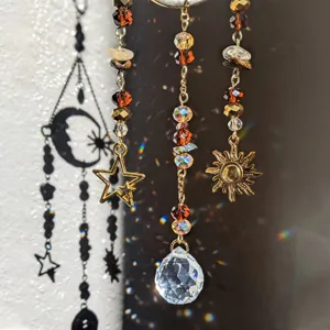 Crystal suncatcher detail shot showing hanging prism beads and metal sun star charms in light.