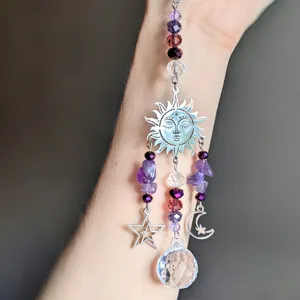 Close-up detail of crystal suncatcher ornament with amethyst beads, sun, moon, and stars.