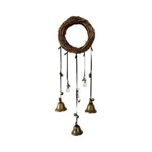 Detail view of bohemian rattan wreath wall hanging with brass bells and glass bottles.