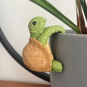 Close-up detail shot of the cute hanging turtle resin figurine decorating a plant pot rim.