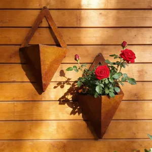Detailaufnahme dreieckiger, rostfarbener Metall-Wandpflanzgefäße mit leuchtend roten Rosen.