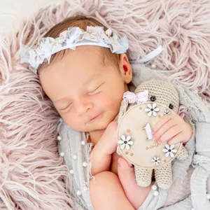 Newborn baby photography prop detailed view showing wooden milestone card and cute headband.