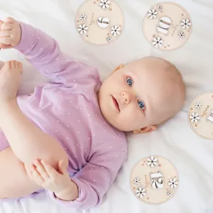Wooden baby monthly milestone cards set with white daisy decor, perfect photo props for newborns.