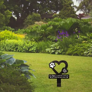 Detalle de estaca conmemorativa para mascotas con corazón, huella y texto emotivo en césped verde.