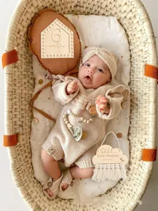 Nordic baby sleeping door sign and cute knitted newborn outfit set for nursery decor.