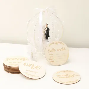 Wooden baby milestone card detail showing monthly growth record discs and engraved text.