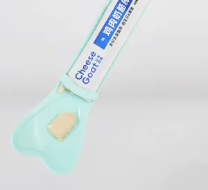 Cat treat spoon detail shot, green plastic dispenser tool and squeeze design for pet food.
