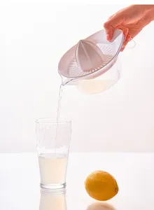 Detailansicht der manuellen Zitruspresse beim Eingiessen von frischem Zitronensaft ins Glas.
