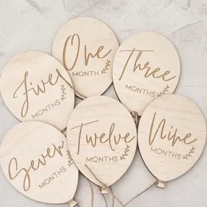 Wooden baby monthly milestone balloon disc detail with engraved English text and twine string.