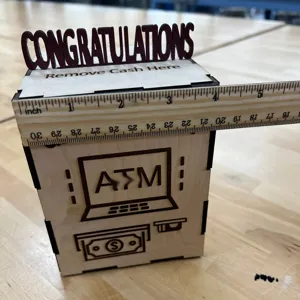 Detalle caja de dinero graduación madera, diseño ATM y adorno de felicitación para fiesta.