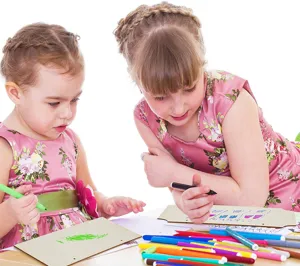 Detailweergave van kinderen die met gekleurde markers op lege houten borden tekenen.