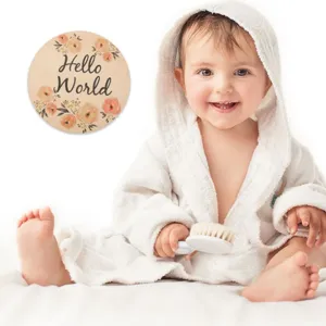 Wooden baby milestone disc detail shot with floral design and cute baby prop setup for photos.