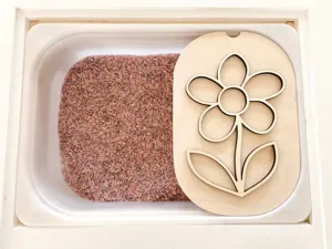 Primer plano de bandeja sensorial de madera con forma de flor y arroz de color para decor.
