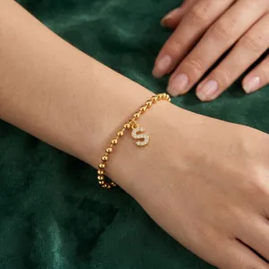 Dettaglio in primo piano del bracciale di perle in acciaio inossidabile con lettera S.