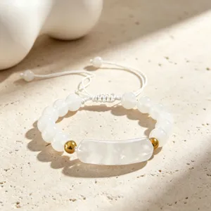Nahaufnahme des weißen Perlenarmbands mit goldenen Perlen und einem zentralen Brückenanhänger.