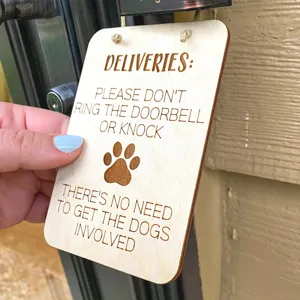 Detalle de placa de puerta de madera para perros con texto grabado y huella de pata.