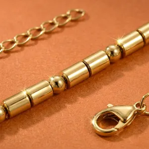 Detaillierte Aufnahme eines goldenen Roehrchen- und Perlenketten-Armbands aus Edelstahl.