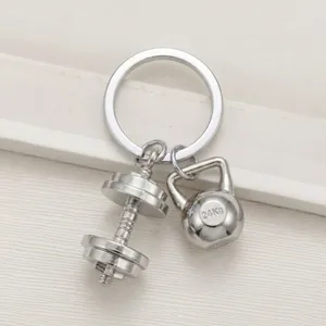 Detailed shot of silver metal dumbbell and kettlebell keychain, fitness accessory pendant keyring.
