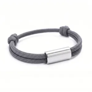 Detailed close-up of a grey handmade braided paracord bracelet with a polished stainless steel tube.