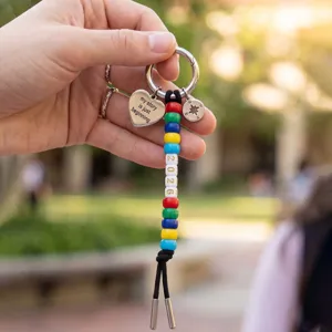Detail shot of graduation keychain featuring colorful beads, 2026 charm, and compass pendant.
