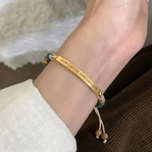 Gros plan sur la barre en métal gravée et le bracelet de perles en pierre naturelle.