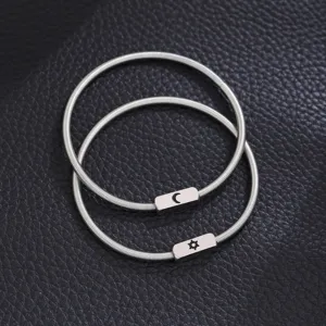 Close-up detail of silver stainless steel spring couple bracelets with sun and moon charms.